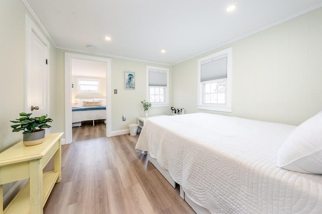 bedroom featuring crown molding, multiple windows, and light wood-type flooring