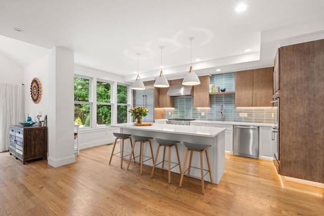 321-323 Lake Ave Unit 323, Newton, MA 02461 - kitchen featuring appliances with stainless steel finishes, light countertops, wall chimney exhaust hood, light wood finished floors, and recessed lighting