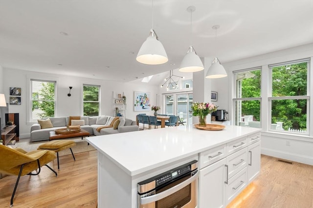 321-323 Lake Ave Unit 323, Newton, MA 02461 - kitchen featuring stainless steel oven, light wood-style flooring, white cabinetry, light countertops, and a center island