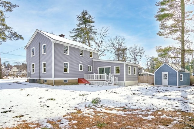 snow covered back of property featuring an outdoor structure, a deck, and central air condition unit