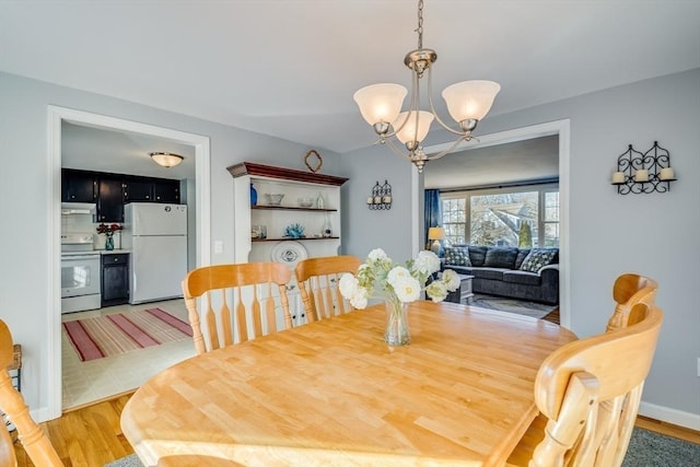 dining space with light wood-type flooring and an inviting chandelier