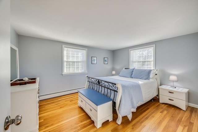 bedroom featuring a baseboard heating unit and light hardwood / wood-style floors