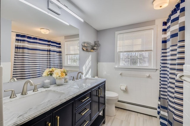 bathroom with tile walls, vanity, a baseboard heating unit, walk in shower, and toilet