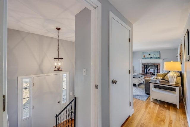 hallway with an inviting chandelier and light wood-type flooring