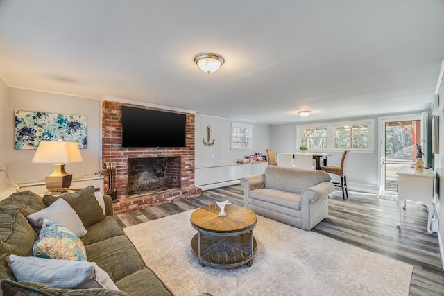 living room featuring hardwood / wood-style flooring, ornamental molding, a fireplace, and baseboard heating