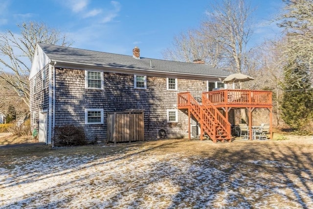 snow covered rear of property with a deck