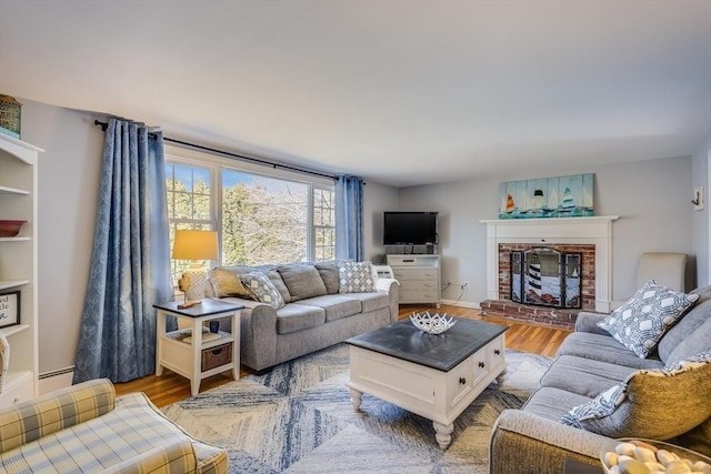 living room with a brick fireplace, a baseboard radiator, and light wood-type flooring