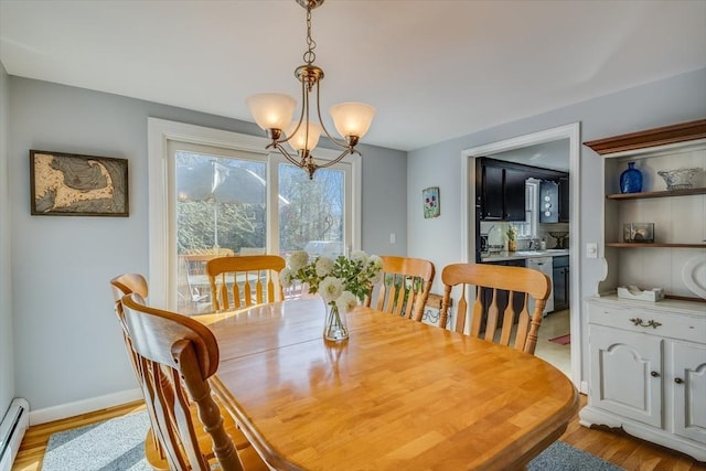 dining room with a notable chandelier, baseboard heating, and light hardwood / wood-style flooring