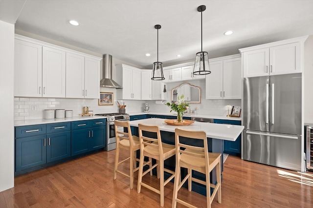 11 Bailey Pond Ln Unit 11, Amesbury, MA 01913 - kitchen with appliances with stainless steel finishes, blue cabinets, wall chimney range hood, light countertops, and a kitchen bar