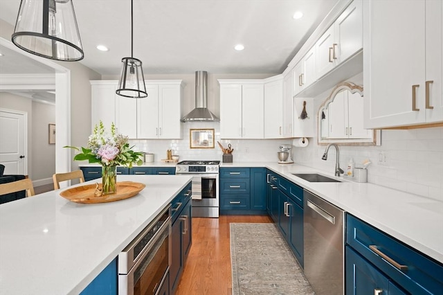 11 Bailey Pond Ln Unit 11, Amesbury, MA 01913 - kitchen with blue cabinetry, wall chimney exhaust hood, appliances with stainless steel finishes, a sink, and light wood-type flooring