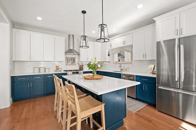 11 Bailey Pond Ln Unit 11, Amesbury, MA 01913 - kitchen featuring stainless steel appliances, blue cabinetry, wall chimney range hood, a breakfast bar area, and a center island