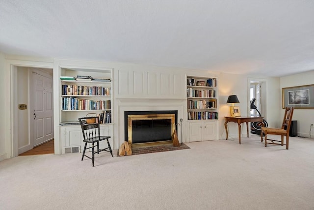 sitting room featuring built in shelves and light colored carpet