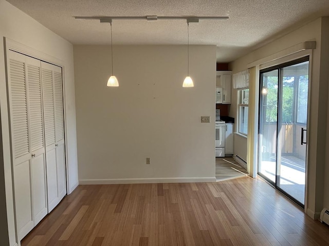 14 Harold St Unit D, Harwich, MA 02646 - unfurnished dining area featuring wood finished floors, a textured ceiling, and a baseboard radiator