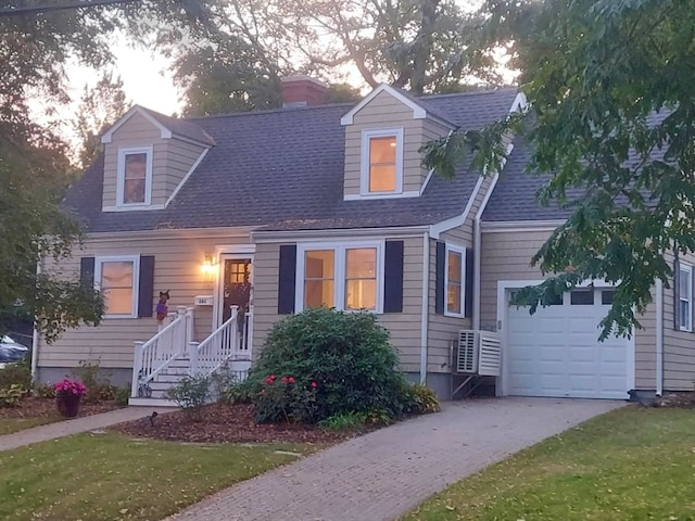 cape cod house featuring a garage and a lawn