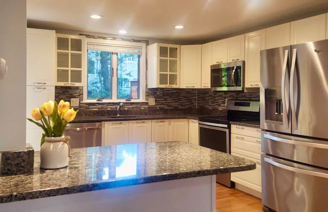 kitchen with white cabinets, dark stone countertops, sink, and stainless steel appliances