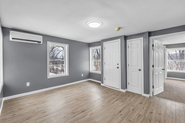 unfurnished bedroom featuring a wall mounted air conditioner, wood finished floors, and baseboards