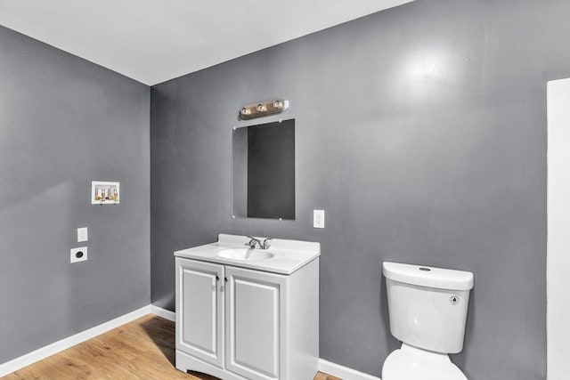 bathroom with vanity, wood finished floors, toilet, and baseboards