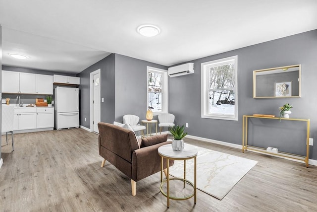 living room featuring light wood-type flooring, baseboards, and an AC wall unit