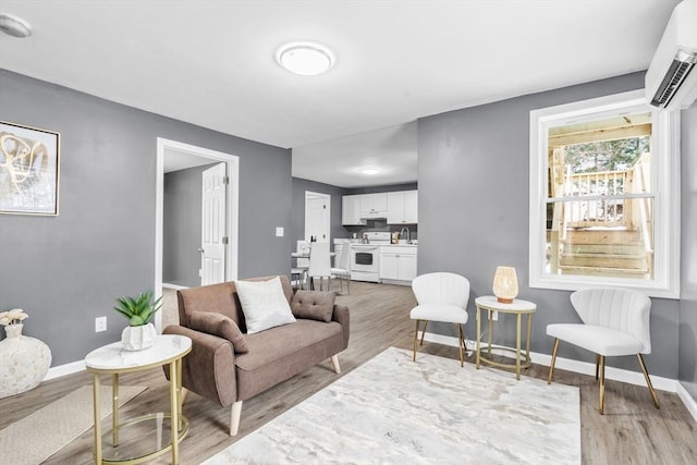 living area with light wood-style flooring, baseboards, and a wall mounted AC