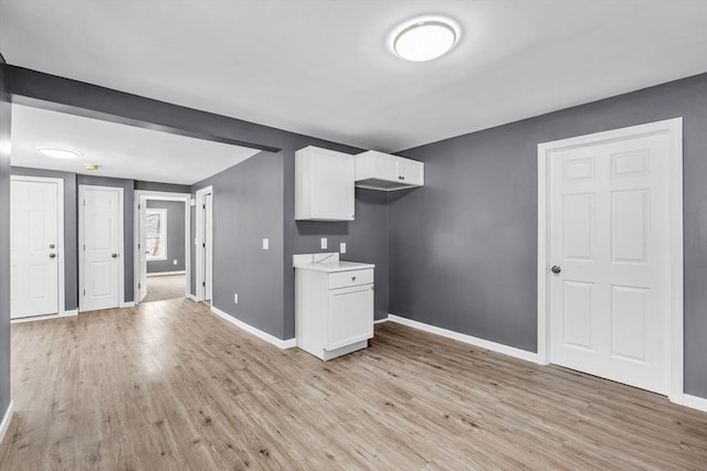 kitchen with baseboards, light wood finished floors, and white cabinets