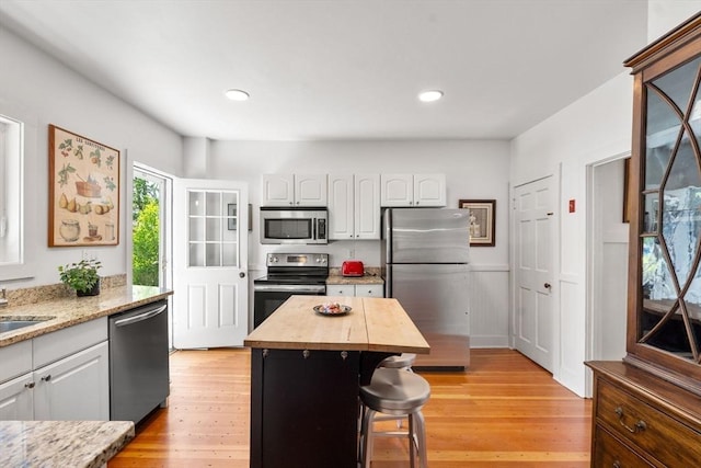 250 Arlington St Unit A, Acton, MA 01720 - kitchen featuring appliances with stainless steel finishes, wooden counters, white cabinetry, light wood-style flooring, and a wainscoted wall