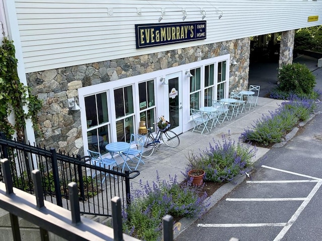250 Arlington St Unit A, Acton, MA 01720 - view of exterior entry with stone siding, a patio area, and uncovered parking