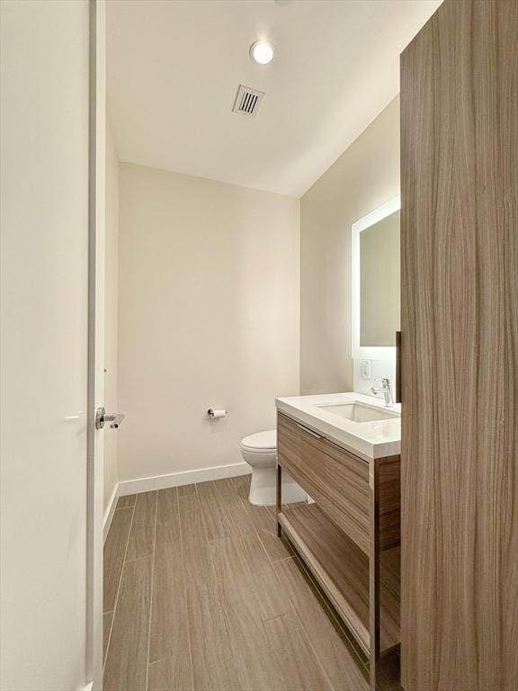 bathroom featuring wood-type flooring, vanity, and toilet