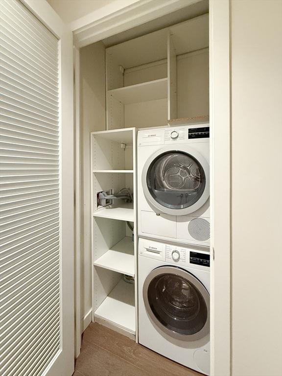 laundry area featuring light wood-type flooring and stacked washer and dryer