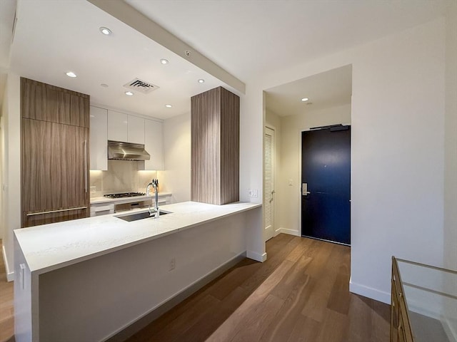 kitchen featuring white cabinetry, sink, stainless steel gas cooktop, hardwood / wood-style floors, and a kitchen island with sink