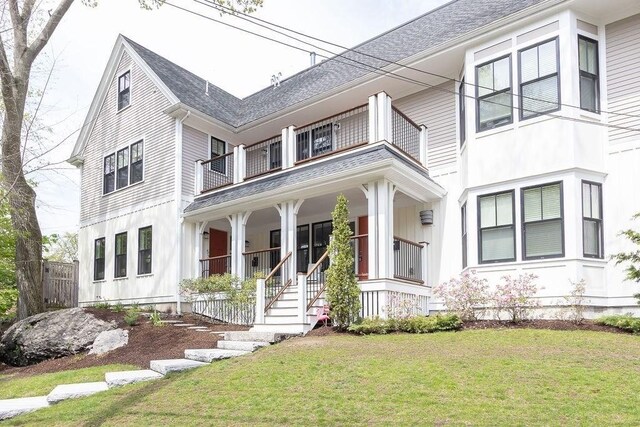 view of front of house with a balcony, a porch, a front yard, and roof with shingles