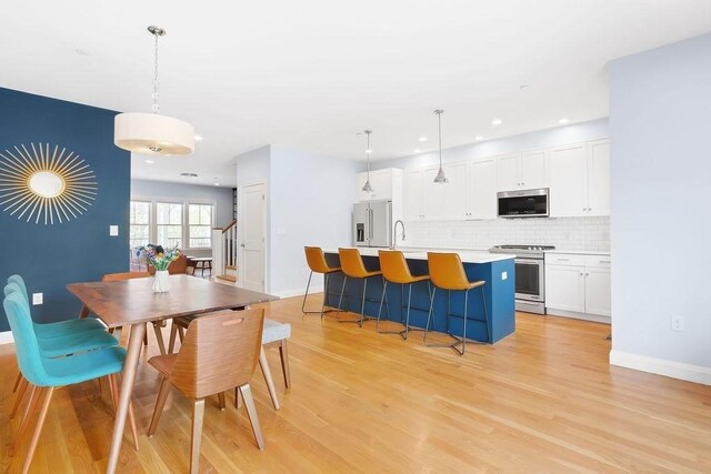 dining space with light wood-style flooring, recessed lighting, and baseboards