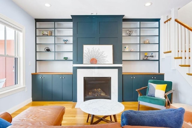 sitting room featuring stairway, a premium fireplace, light wood-style floors, recessed lighting, and baseboards