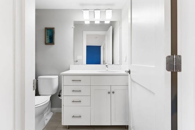 bathroom featuring toilet, vanity, baseboards, and tile patterned flooring