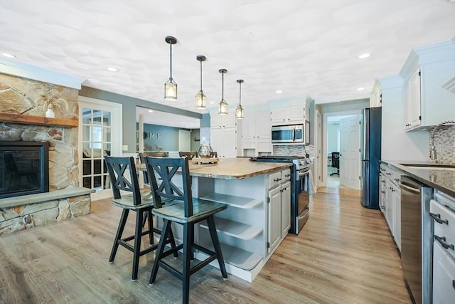 kitchen with appliances with stainless steel finishes, white cabinetry, a kitchen island, pendant lighting, and backsplash