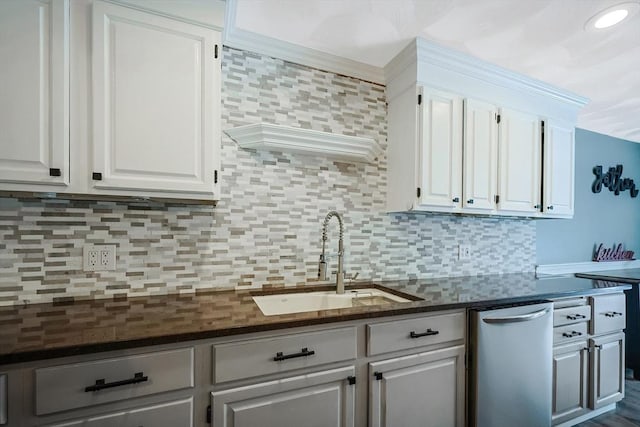 kitchen featuring white cabinets, backsplash, ornamental molding, and sink