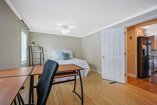 bedroom with ceiling fan, light hardwood / wood-style flooring, black fridge, and crown molding