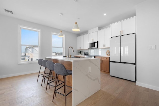 437-439 Chelsea St Unit 3R, Boston, MA 02128 - kitchen with freestanding refrigerator, stainless steel microwave, light wood-style flooring, an island with sink, and recessed lighting