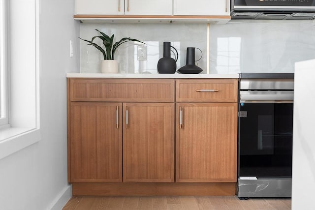 437-439 Chelsea St Unit 3R, Boston, MA 02128 - detailed view of electric range, light countertops, ventilation hood, and light wood-type flooring