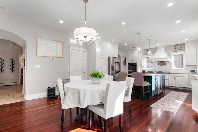 dining room with dark wood-type flooring, beverage cooler, baseboard heating, and a notable chandelier