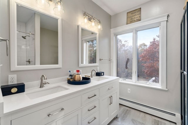 bathroom with vanity, baseboard heating, and a healthy amount of sunlight