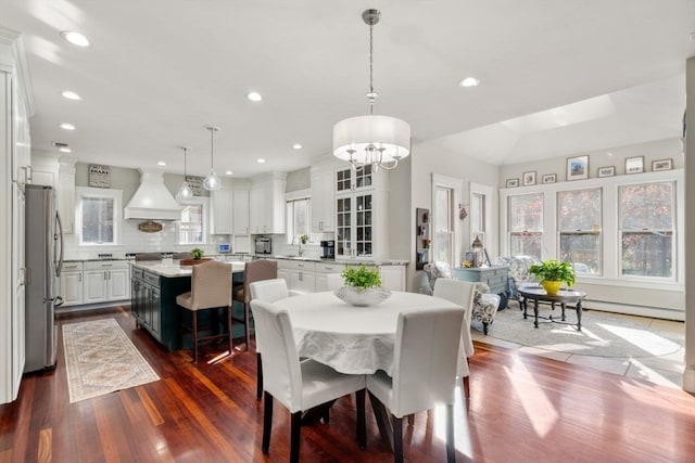 dining space with dark hardwood / wood-style flooring, sink, baseboard heating, and a notable chandelier