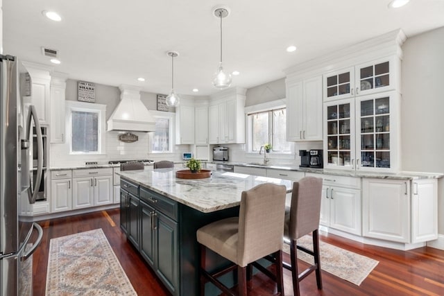 kitchen with stainless steel appliances, a kitchen island, custom range hood, dark hardwood / wood-style flooring, and white cabinets