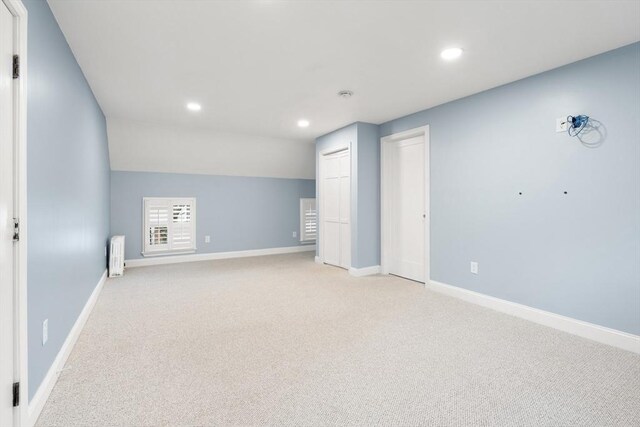 spare room featuring baseboards, recessed lighting, radiator heating unit, and light carpet