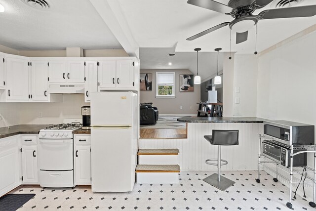kitchen with visible vents, dark countertops, white appliances, under cabinet range hood, and white cabinets