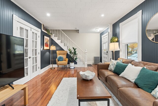 living area with french doors, crown molding, wood finished floors, stairway, and radiator