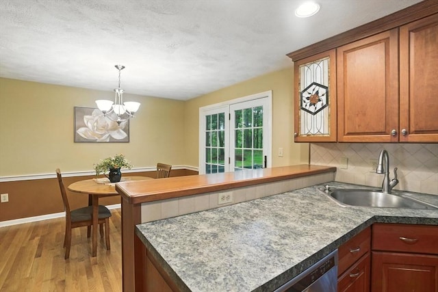 814 Wellman Ave Unit 814, Chelmsford, MA 01863 - kitchen featuring light wood-style floors, a peninsula, backsplash, stainless steel dishwasher, and a chandelier