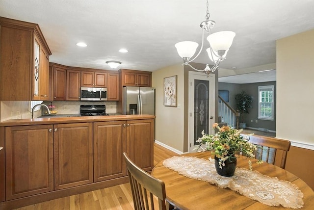 814 Wellman Ave Unit 814, Chelmsford, MA 01863 - kitchen featuring appliances with stainless steel finishes, brown cabinetry, a chandelier, light wood-style flooring, and decorative backsplash