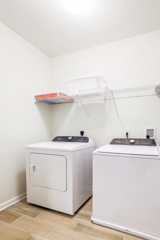 clothes washing area with washer and dryer and light wood-type flooring