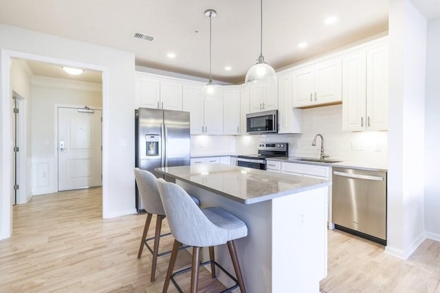 kitchen featuring a kitchen island, white cabinetry, appliances with stainless steel finishes, and sink