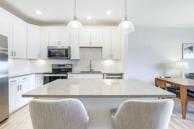 kitchen with stainless steel appliances, sink, pendant lighting, and white cabinets